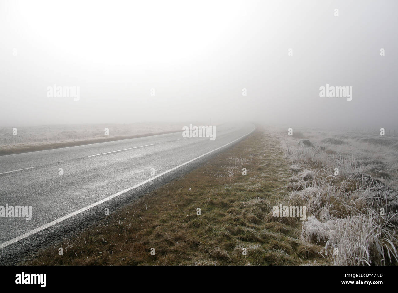 Une route vers nulle part ? Afficher le long de la route dans la brume avec frosty avant-plan. Banque D'Images