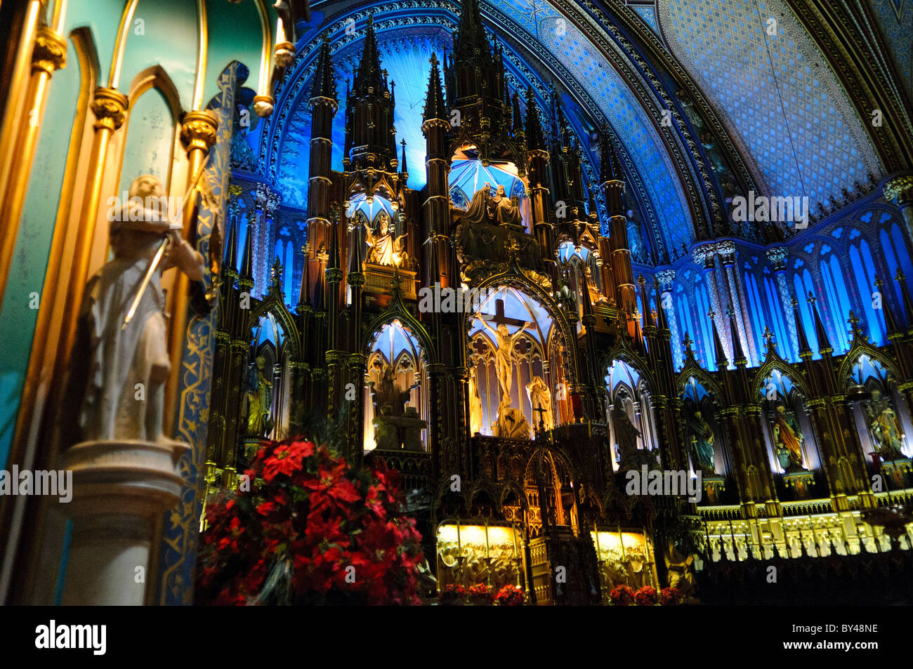 Autel principal de la basilique notre-Dame Montréal Canada // MONTRÉAL, Canada — le maître-autel et le sanctuaire de la basilique notre-Dame présentent un savoir-faire exceptionnel du renouveau gothique avec son autel en bois de tilleul sculpté et son plafond voûté bleu spectaculaire décoré d'étoiles dorées. Le sanctuaire, redessiné par Victor Bourgeau dans les années 1870, présente une riche palette de couleurs bleues, azures, rouges, violettes, argentées, et de l'or. Ce chef-d'œuvre de l'architecture religieuse est l'un des intérieurs d'église les plus impressionnants d'Amérique du Nord. Banque D'Images
