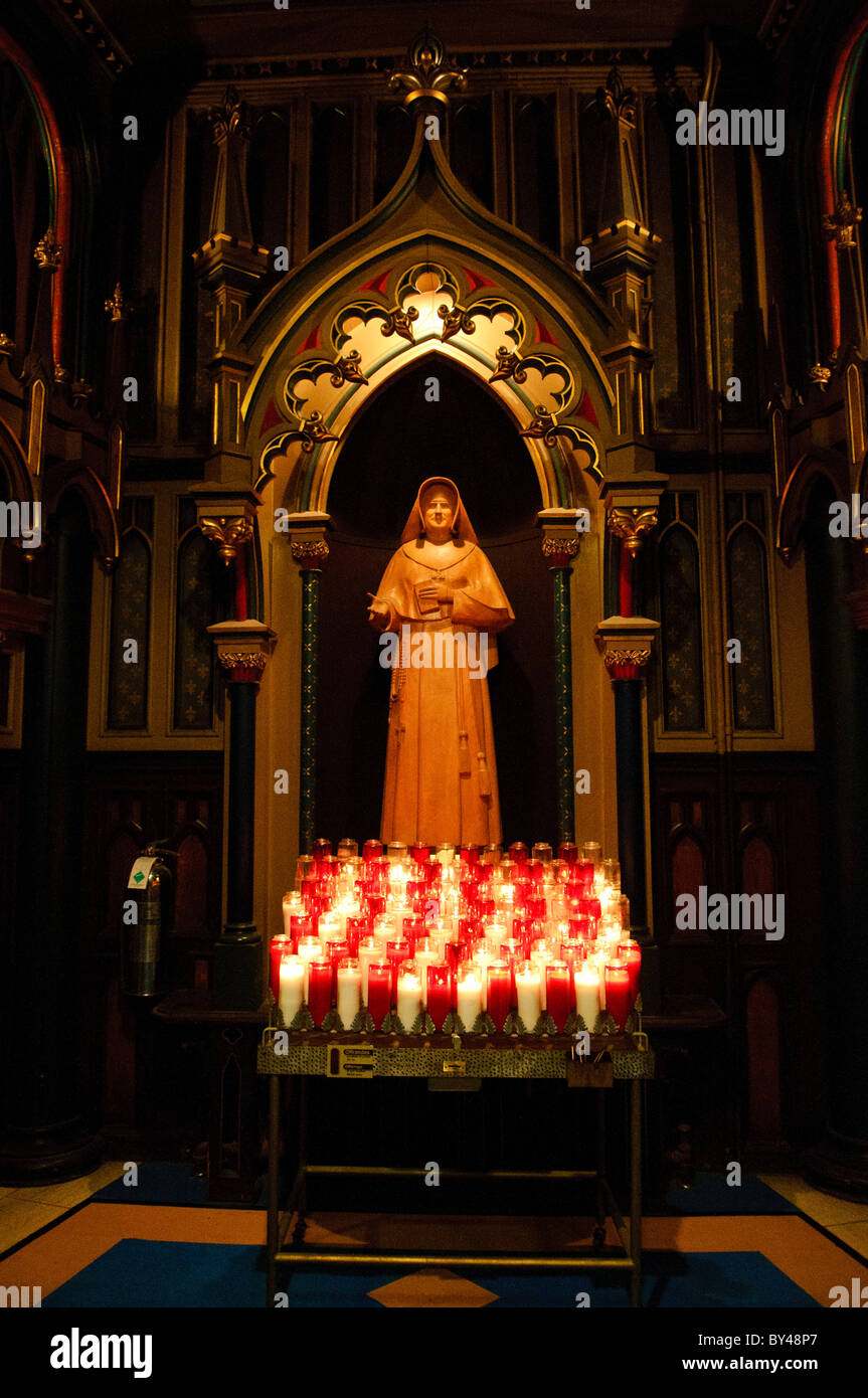 Basilique notre-Dame de Montréal Statue des religieuses Montréal Canada // MONTRÉAL, Canada — Une statue d'une religieuse se dresse dans l'intérieur orné de la Basilique notre-Dame de Montréal. De nombreuses bougies allumées illuminent l'espace devant la statue, ajoutant à l'atmosphère solennelle. Banque D'Images
