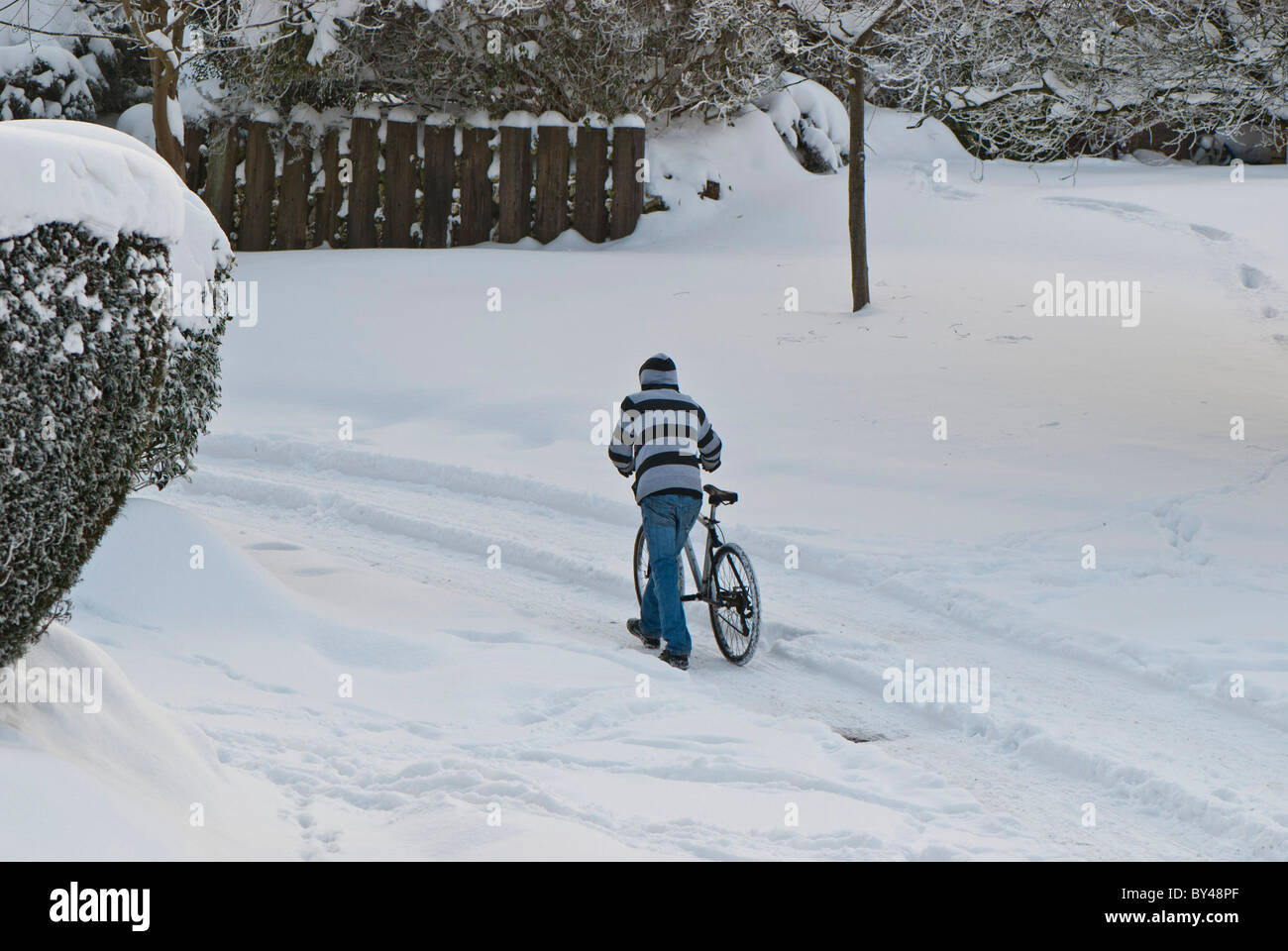 La Grande-Bretagne congelée cycliste solitaire pousse à vélo à travers les rues couvertes de neige Warlingham Surrey, England UK . Banque D'Images