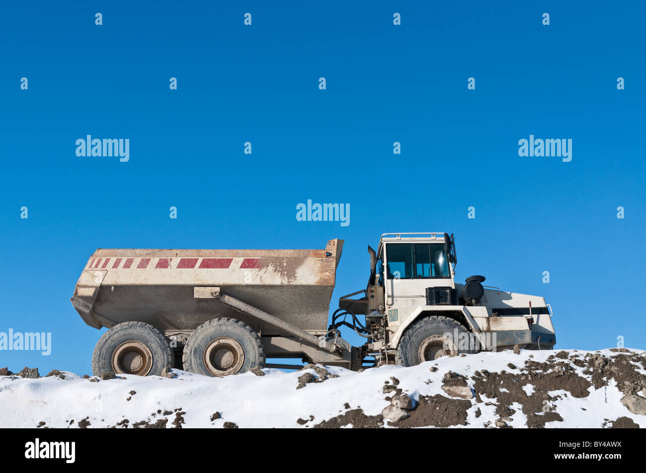 Un camion-benne se trouve au sommet d'un tas de terre sur un site de construction en hiver. Banque D'Images