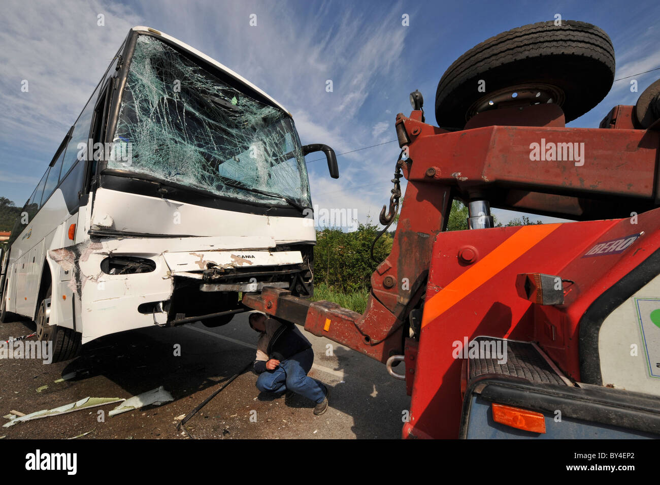 Homme attachant un bus détruit, brisé de verre pare-brise après un accident de voiture à une dépanneuse Banque D'Images