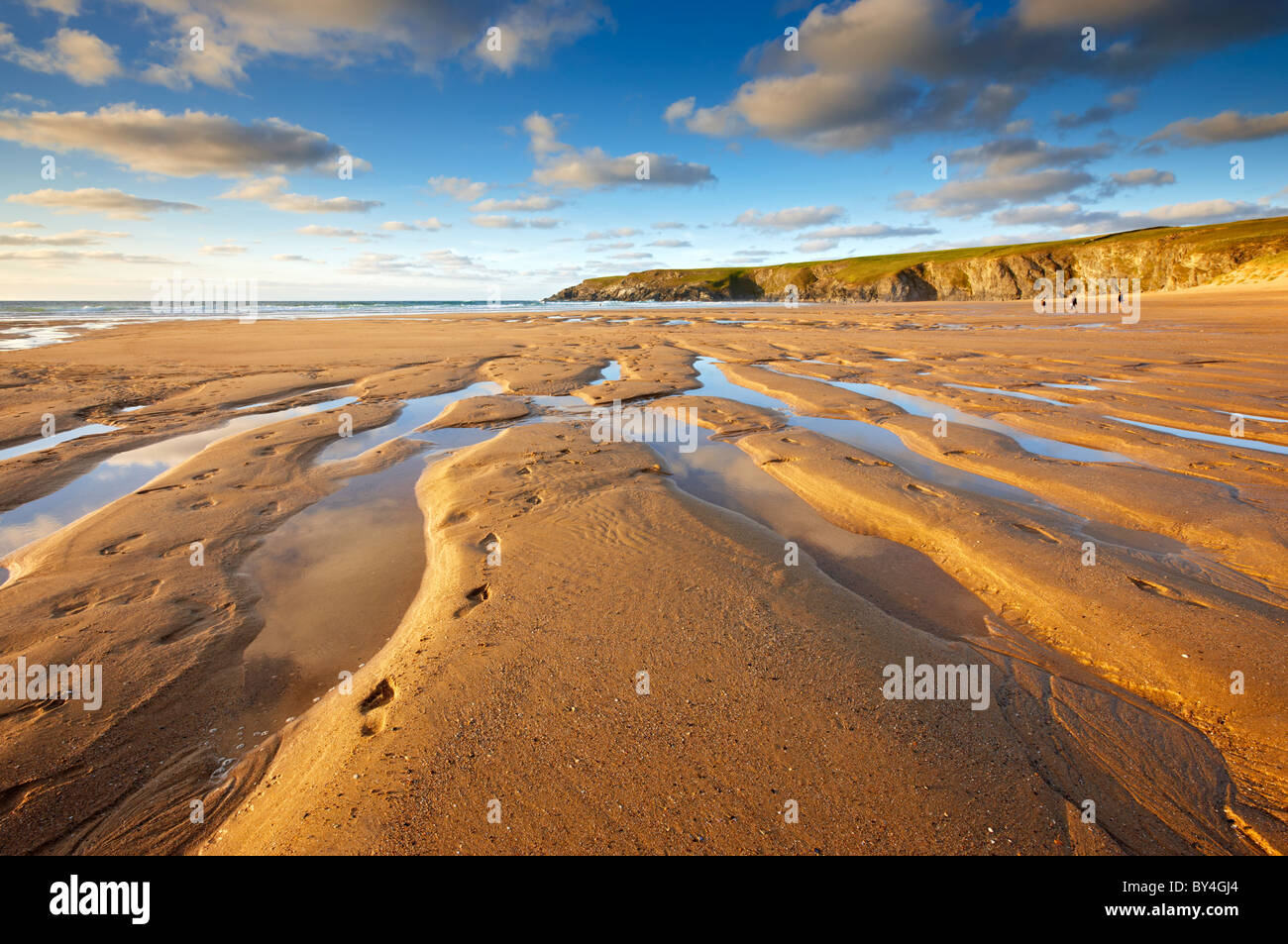 Des traces de pas dans le sable à gauche par les surfeurs, comme ils se précipitent sur la plage et prendre le dernières vagues avant le coucher du soleil à Baie de Holywell Banque D'Images