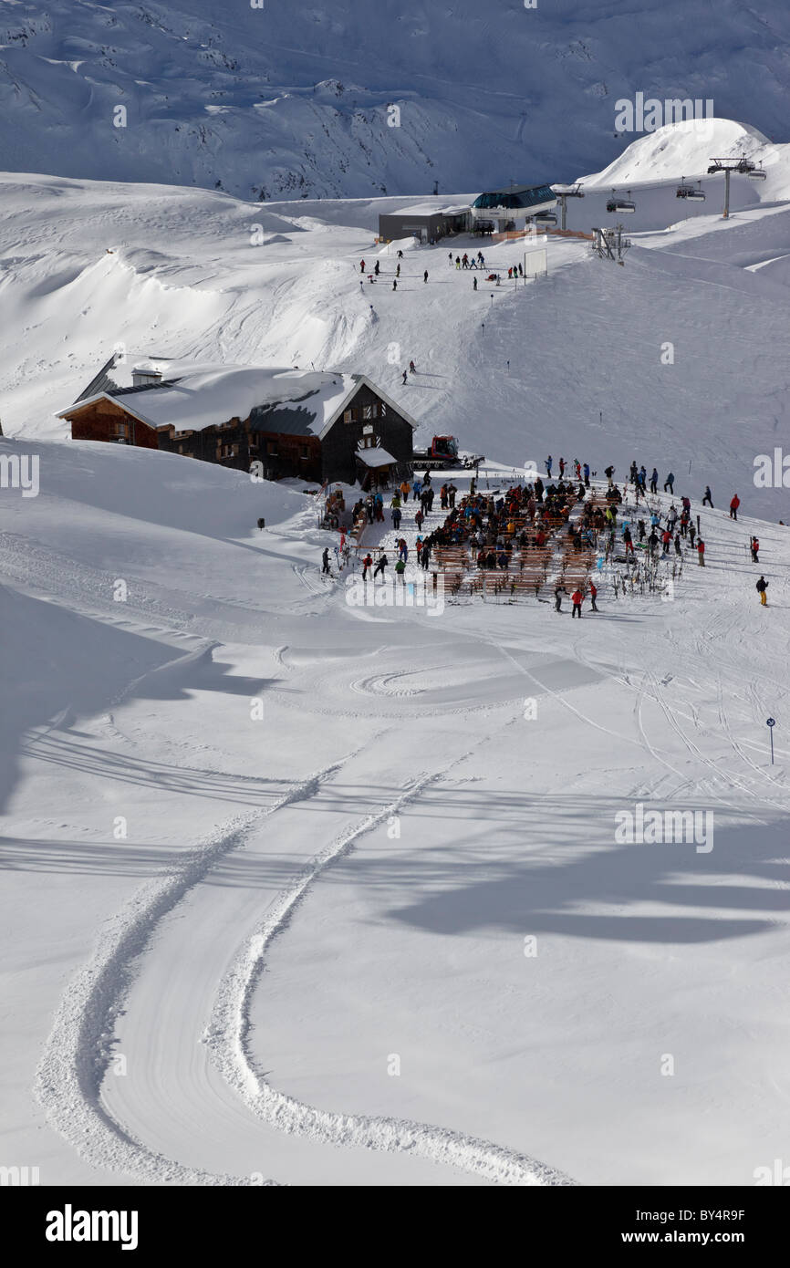 Skieurs et planchistes s'arrêter pour une pause au célèbre Ulmer Hutte à St Anton. Le télésiège Valfagehr est dans la distance. Banque D'Images