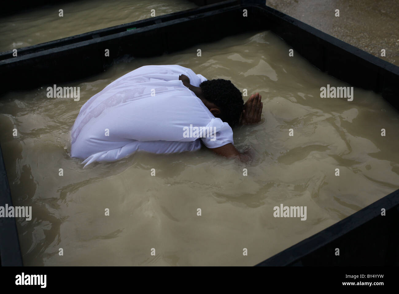 Membre de la communauté chrétienne orthodoxe érythréenne echelle dans le réservoir rempli d'eau du fleuve Jourdain à la cuve baptismale Qaser el Yahud site Kasser aussi Qasser Yehud al ou le nom officiel de la partie occidentale de l'emplacement traditionnel du baptême de Jésus par Jean le Baptiste dans le Jourdain région Vallée de la Cisjordanie Israël Banque D'Images