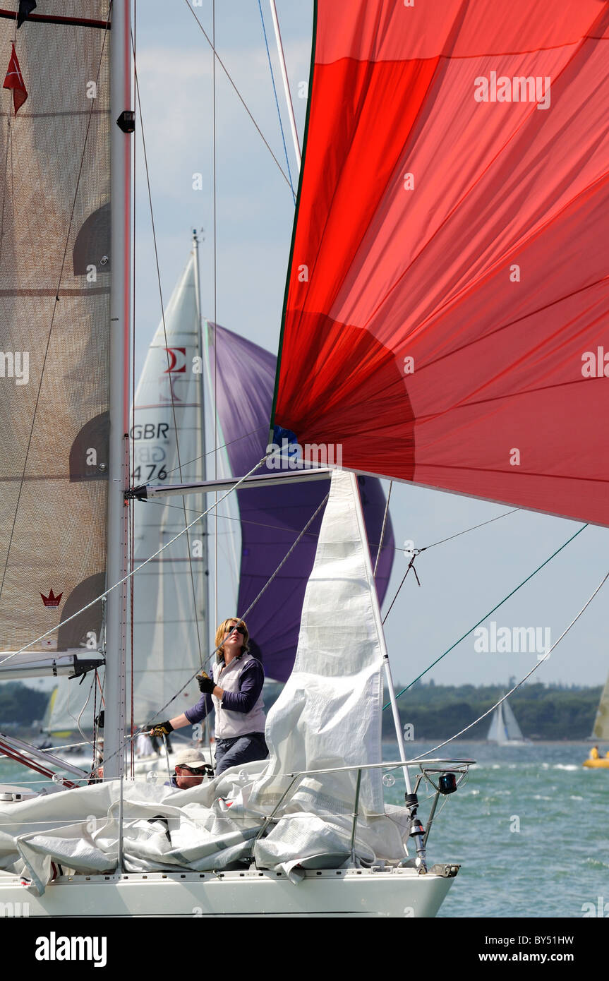 Femme regardant spinnaker rouge pendant la course à la semaine de Cowes, Cowes, île de Wight, Royaume-Uni Banque D'Images