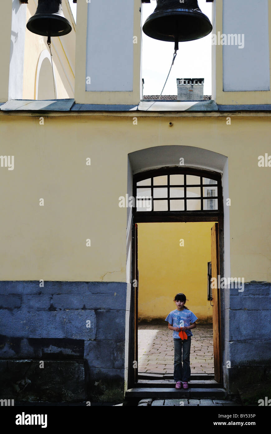 Fille avec avion en papier debout à l'entrée d'une cour de l'église, Lviv, Ukraine Banque D'Images