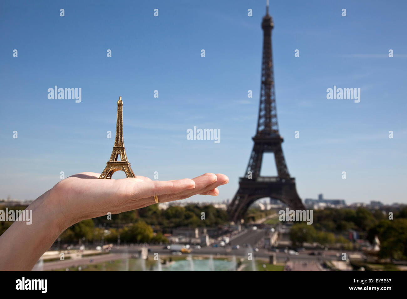Une femme tenant une Tour Eiffel souvenir réplique à côté de la Tour Eiffel, focus on hand Banque D'Images