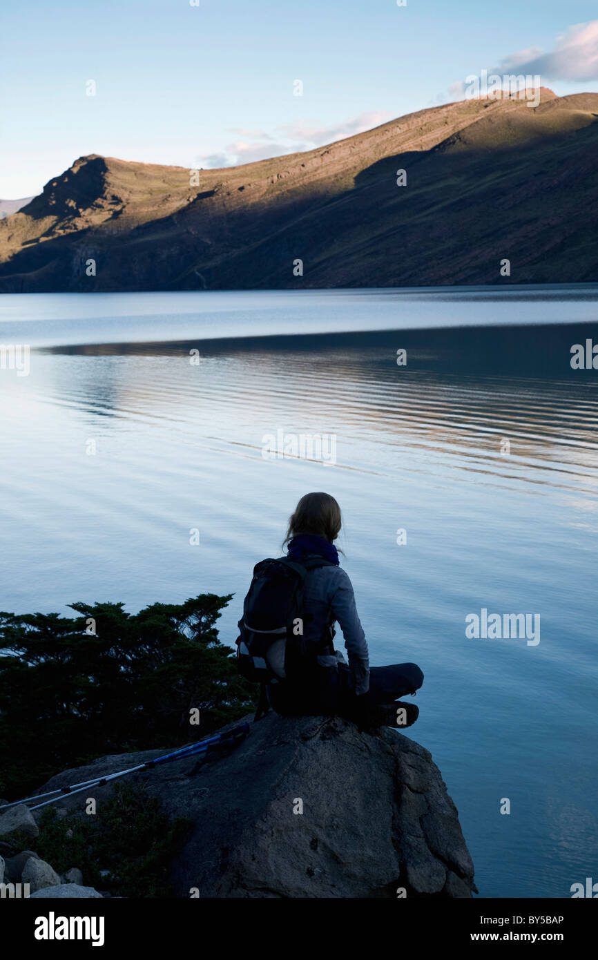 Vue arrière d'une femme assise au bord d'un lac, Parc National Torres del Paine, Chili Banque D'Images