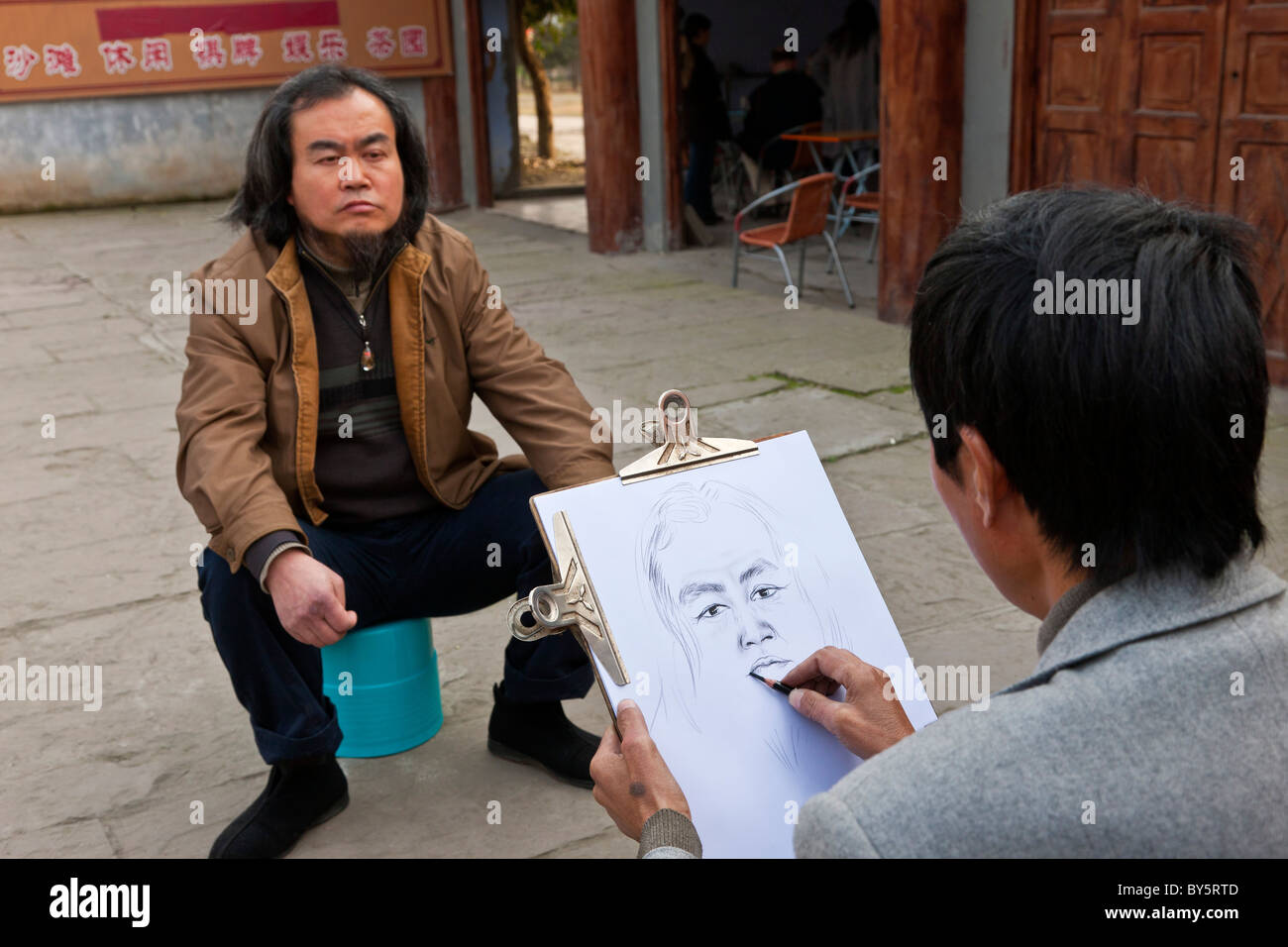 Artiste de rue, de faire un croquis au crayon d'un homme à Huanglongxi, près de Chengdu, province du Sichuan, Chine. JMH4349 Banque D'Images