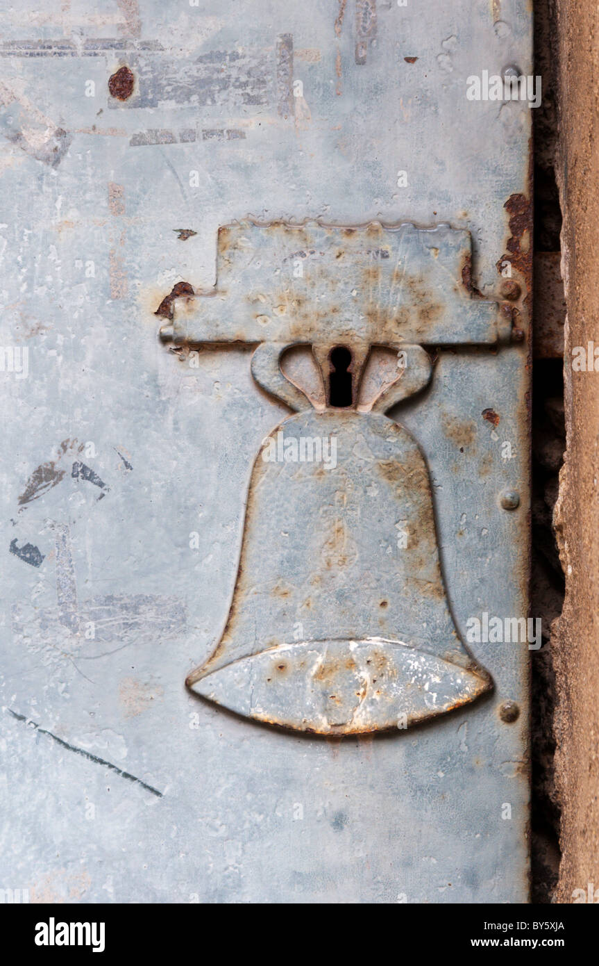 Une plaque d'entrée de clé en forme de cloche sur une porte dans le côté de l'église de St Genies de Fontedit, France Banque D'Images