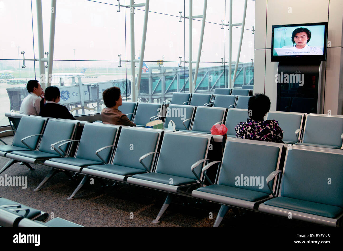 La Chine. Les passagers DE REGARDER LA TÉLÉVISION À LA SALLE D'EMBARQUEMENT DE L'aéroport de Guangzhou Banque D'Images