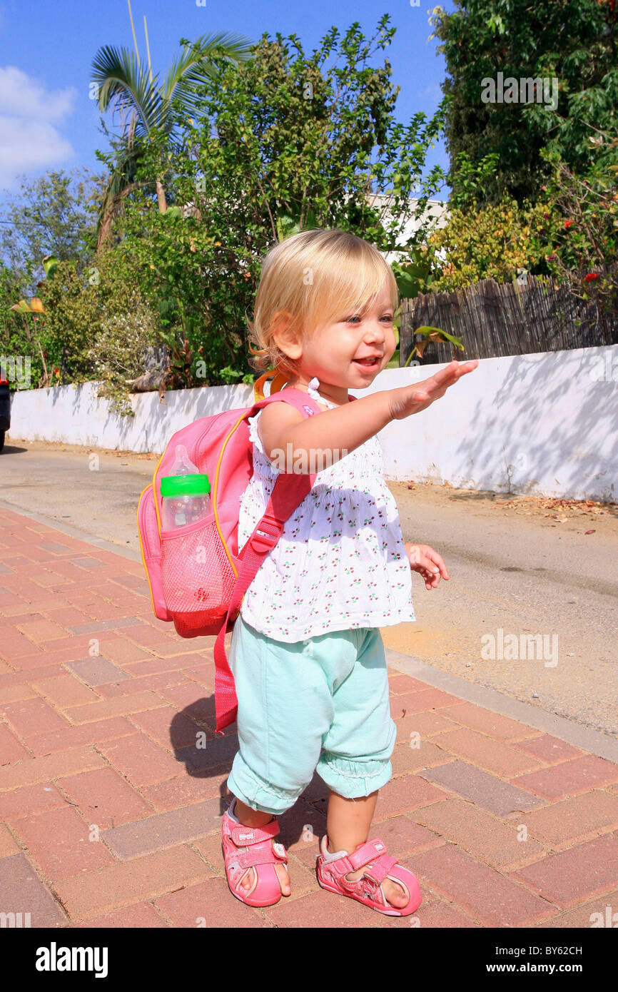 Un bébé fille de 18 mois, avec un petit lunch pack avec bouteille prête  pour la maternelle forme bye-bye Photo Stock - Alamy