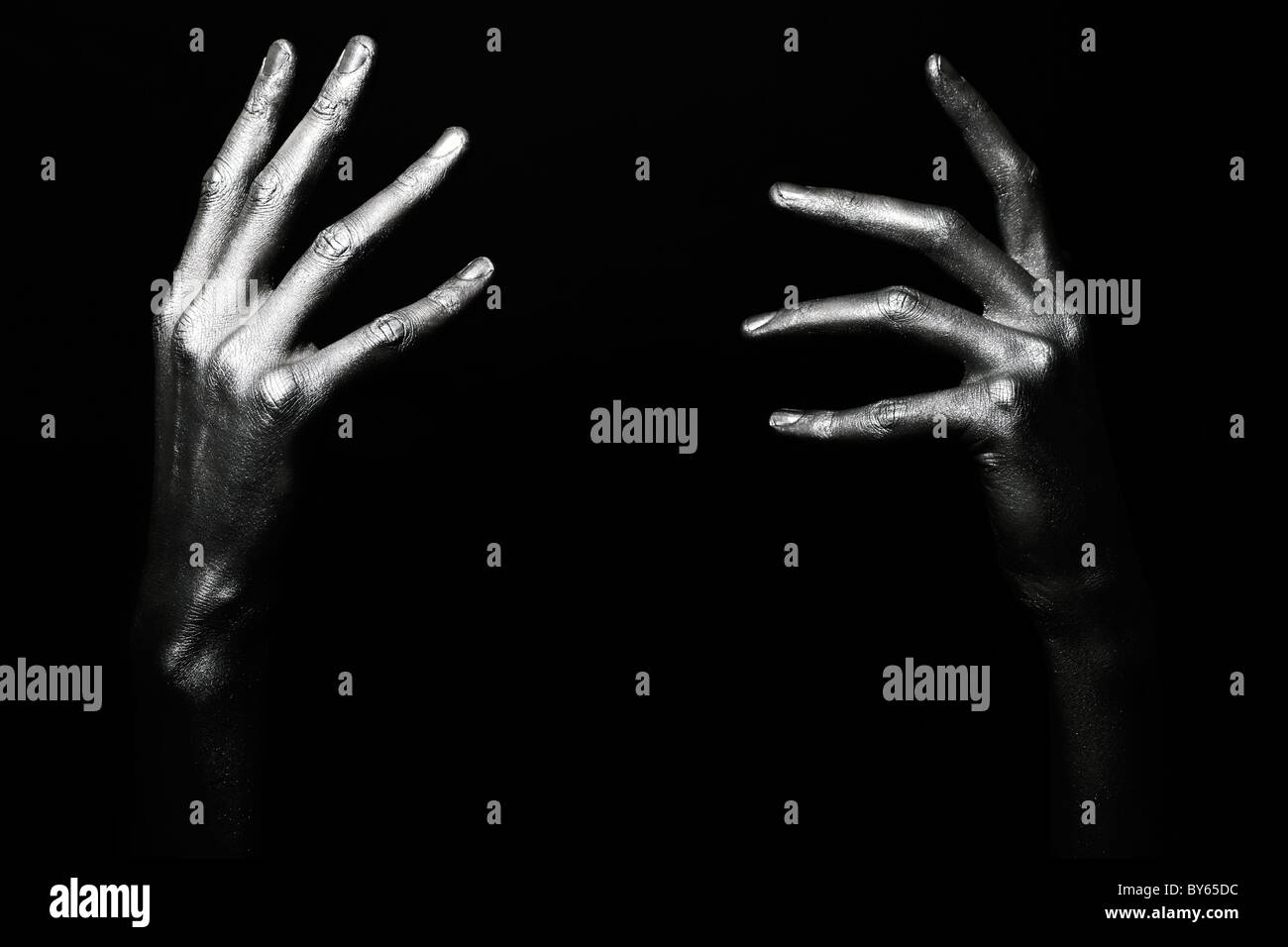 Beau mâle mains dans la peinture argentée sur fond noir Banque D'Images