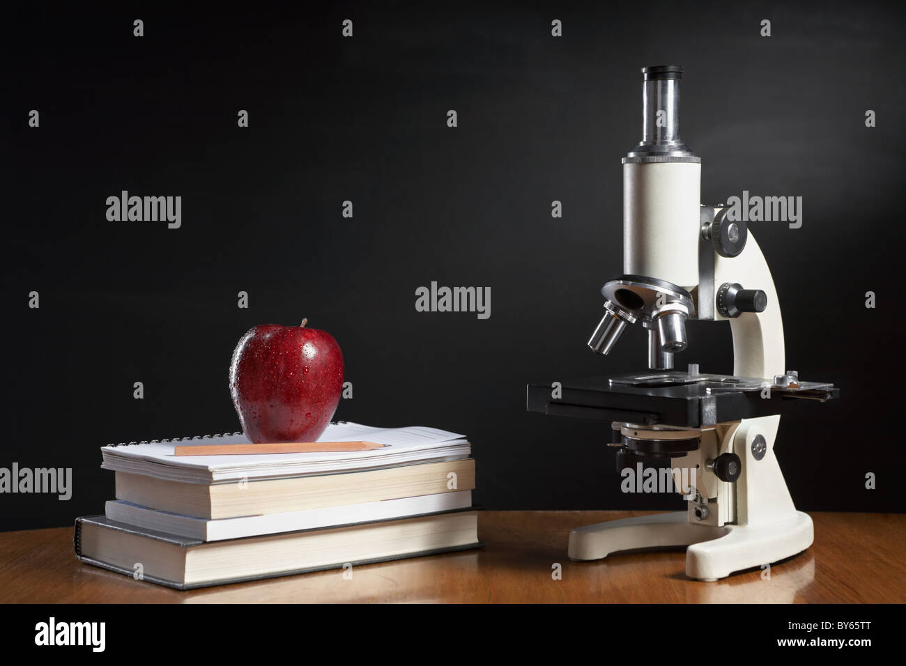 Le concept de classe de biologie à la pomme on pile of books and microscope Banque D'Images