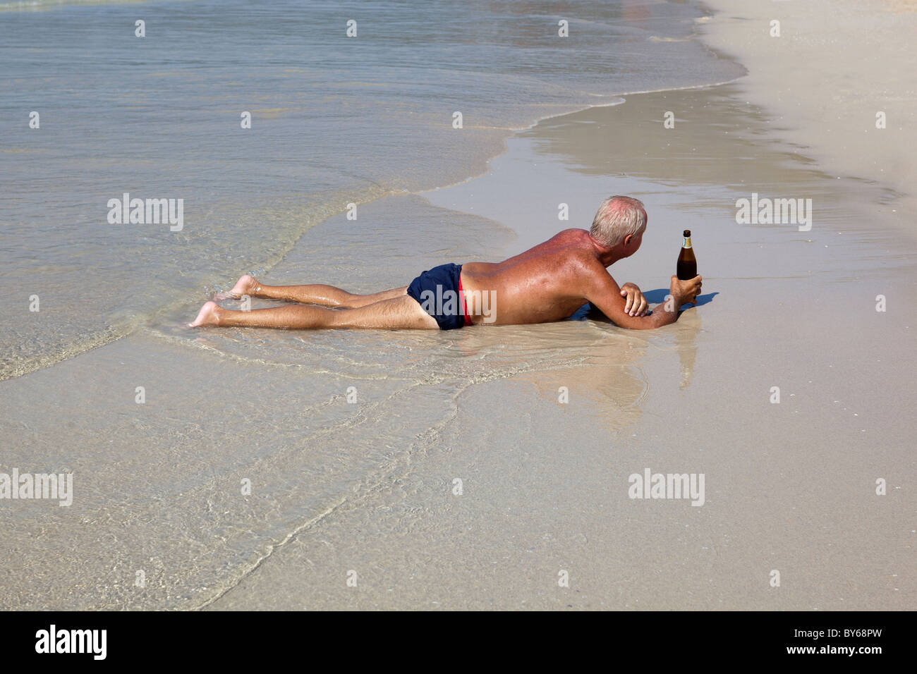 Homme étendu sur la plage de Patpong avec une bouteille de bière Banque D'Images