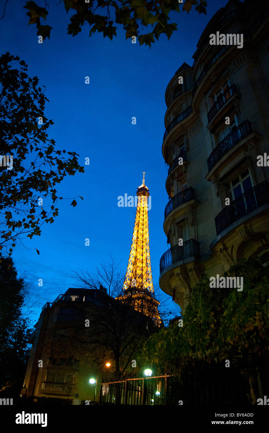 Tour Eiffel illuminée la nuit avec le bâtiment haussmannien Paris France // PARIS, France — la Tour Eiffel est illuminée de lumières dorées et d'un spectacle étincelant la nuit. Un bâtiment haussmannien classique, caractérisé par ses balcons ornés et sa façade en pierre, encadre la structure emblématique. Cette tour en treillis de fer, conçue par Gustave Eiffel, a été achevée en 1889 comme arc d'entrée de l'exposition universelle de 1889. Il mesure 330 mètres (1 083 pieds) de haut, y compris son antenne. La Tour Eiffel est une icône culturelle mondiale et l'un des monuments les plus reconnaissables de France. Banque D'Images
