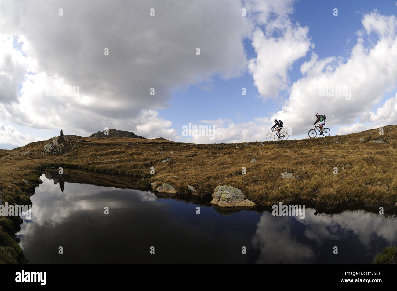 Les gens sur des vélos de montagne au lac de montagne sous ciel nuageux, Markinkele, Saint-Maurice, Val Pusteria, Dolomites, Tyrol du Sud, Italie, Banque D'Images