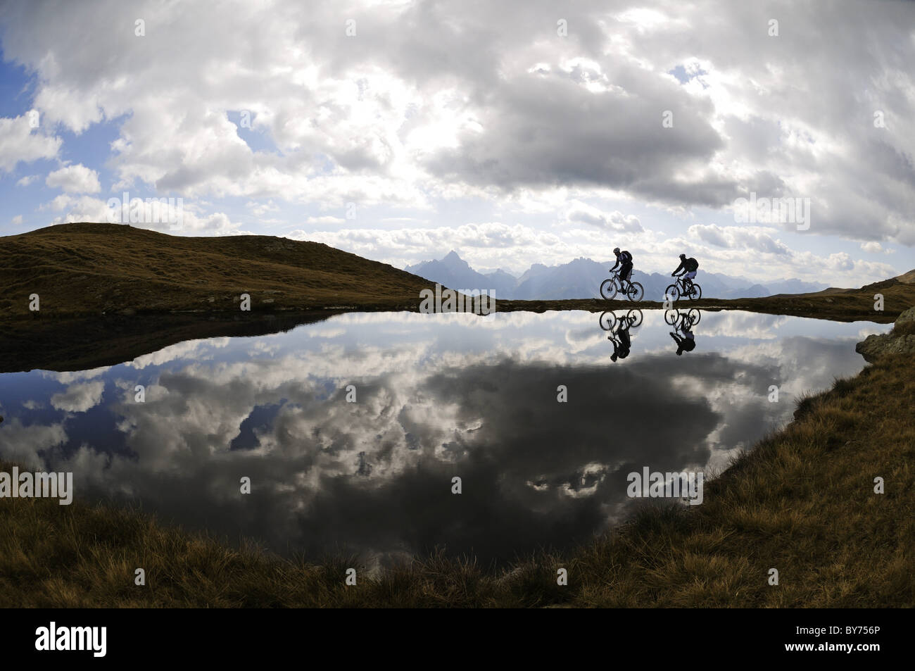 Les gens sur des vélos de montagne au lac de montagne sous ciel nuageux, Markinkele, Saint-Maurice, Val Pusteria, Dolomites, Tyrol du Sud, Italie, Banque D'Images