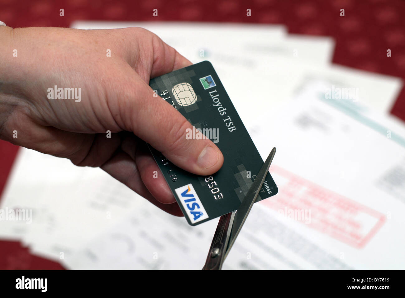 Quelqu'un de couper une carte de crédit, avec des projets en arrière-plan Banque D'Images