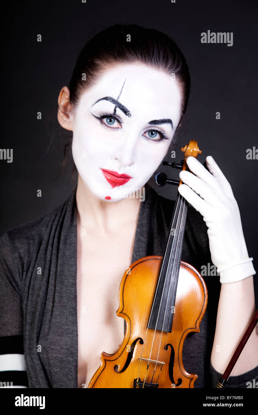 Femme mime avec ancien violon sur fond noir Banque D'Images