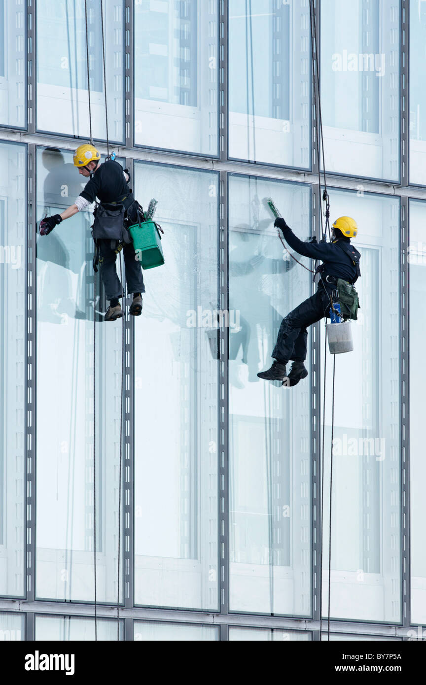 Deux laveurs de vitres sur des cordes suspendues, nettoyer les fenêtres de la BBC Ecosse bureaux, Pacific Quay, Glasgow, Ecosse, Royaume-Uni. Banque D'Images