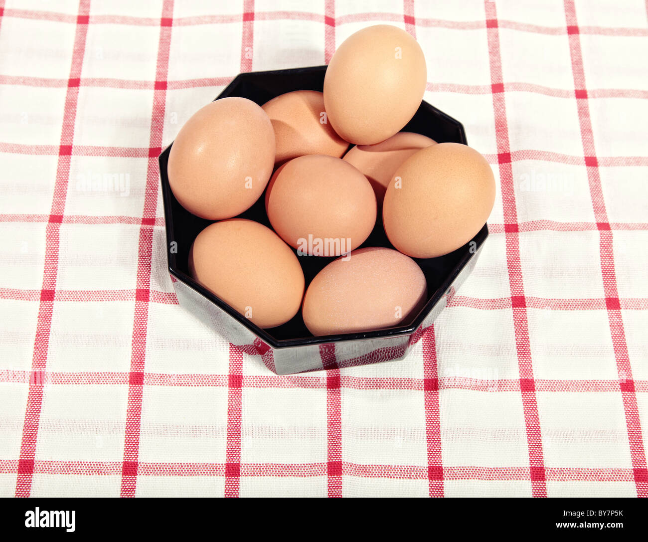 Les oeufs de poule dans un bol noir sur un tissu cellulaire en rouge Banque D'Images