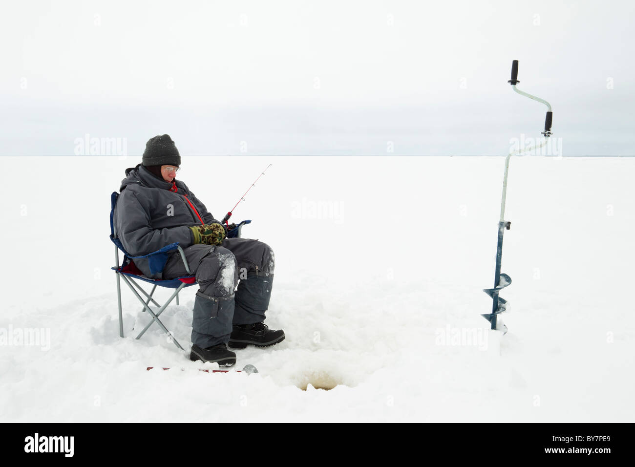 Un pêcheur sur glace assis et regarder son trou à Red Lake dans le nord du Minnesota. Banque D'Images