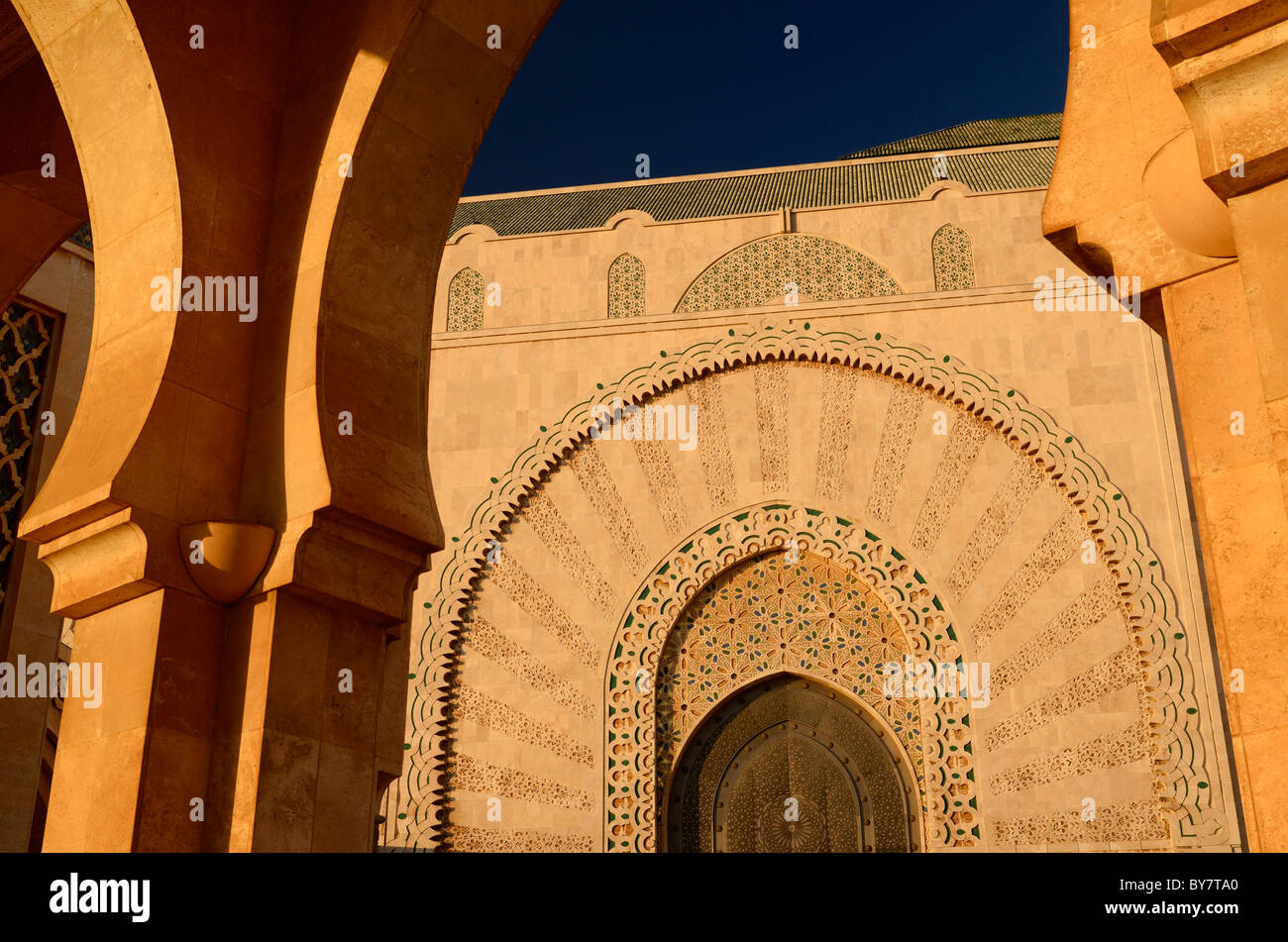 La porte de la mosquée Hassan II casablanca au coucher du soleil vu à travers une voûte en pierre au Maroc Banque D'Images