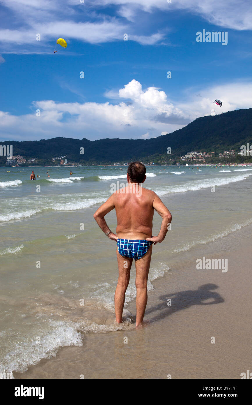 Homme plus âgé en speedos standing on beach at Patong Phuket Thailande Banque D'Images