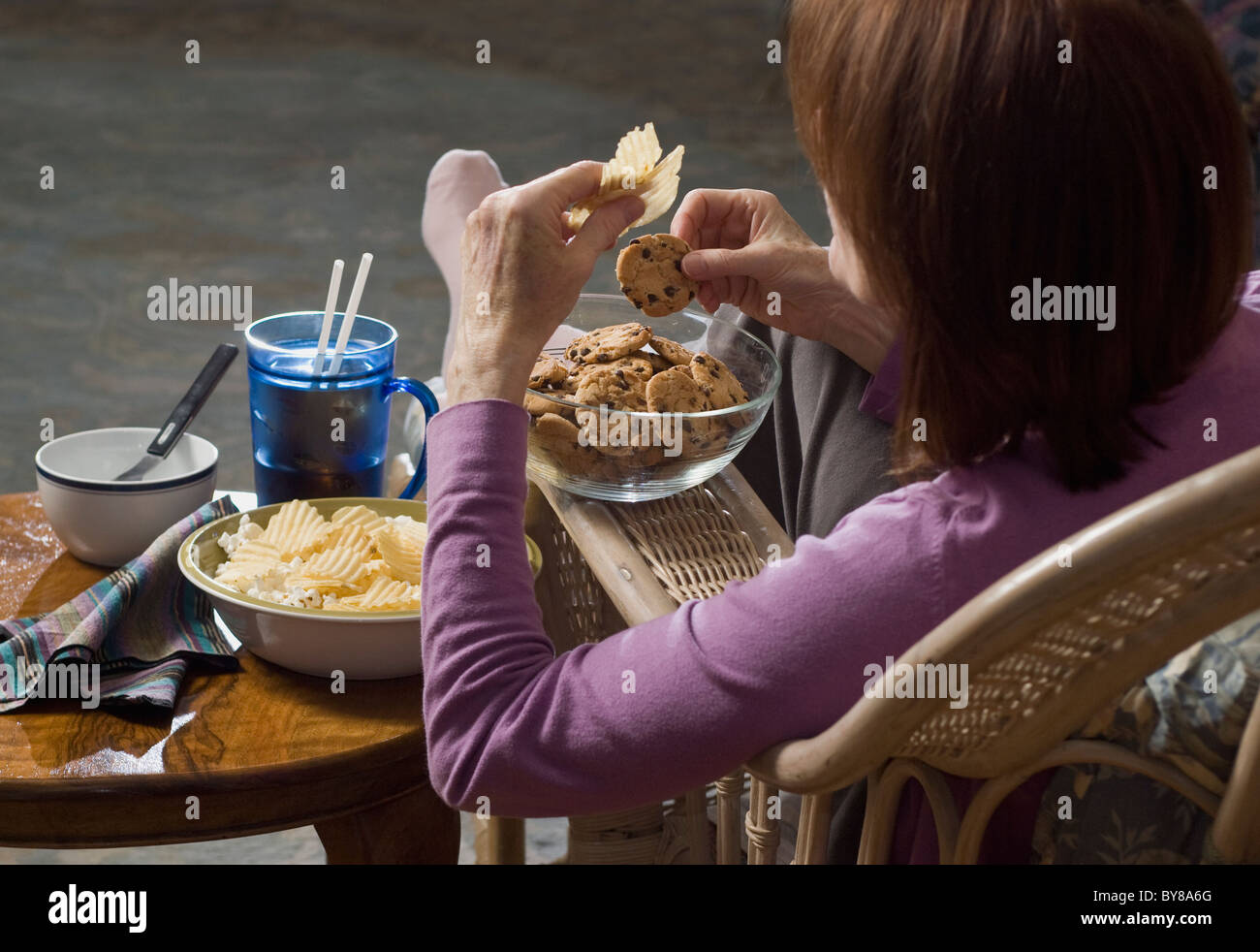 Femme assise de manger de la malbouffe Banque D'Images
