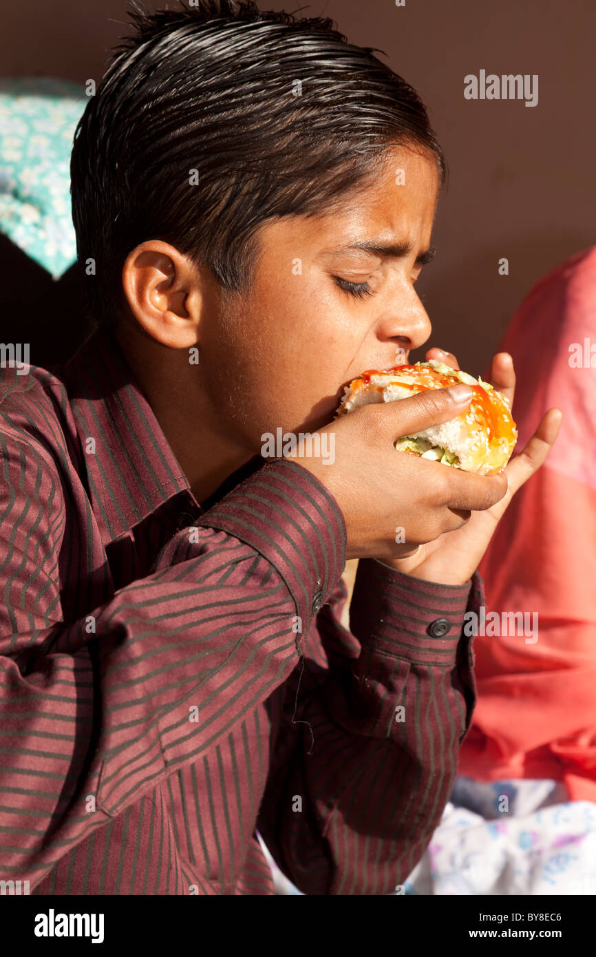 L'Inde, Uttar Pradesh, Agra, Indian boy eating fast food western Banque D'Images