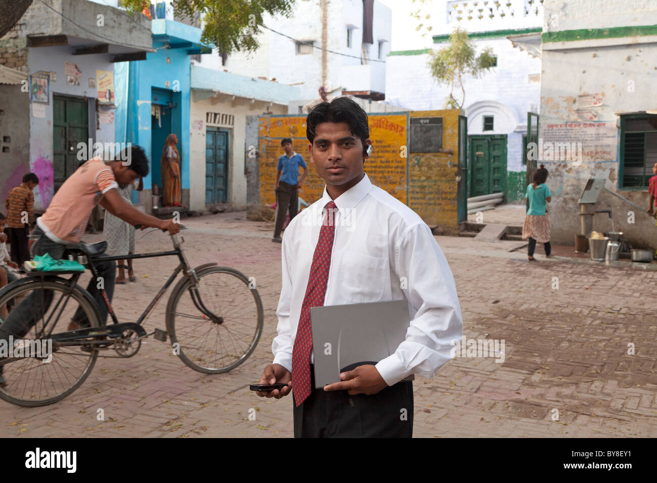 L'Inde, Uttar Pradesh, Agra, homme d'affaires indien en costume et cravate holding laptop et mobiles avec casque Bluetooth Banque D'Images