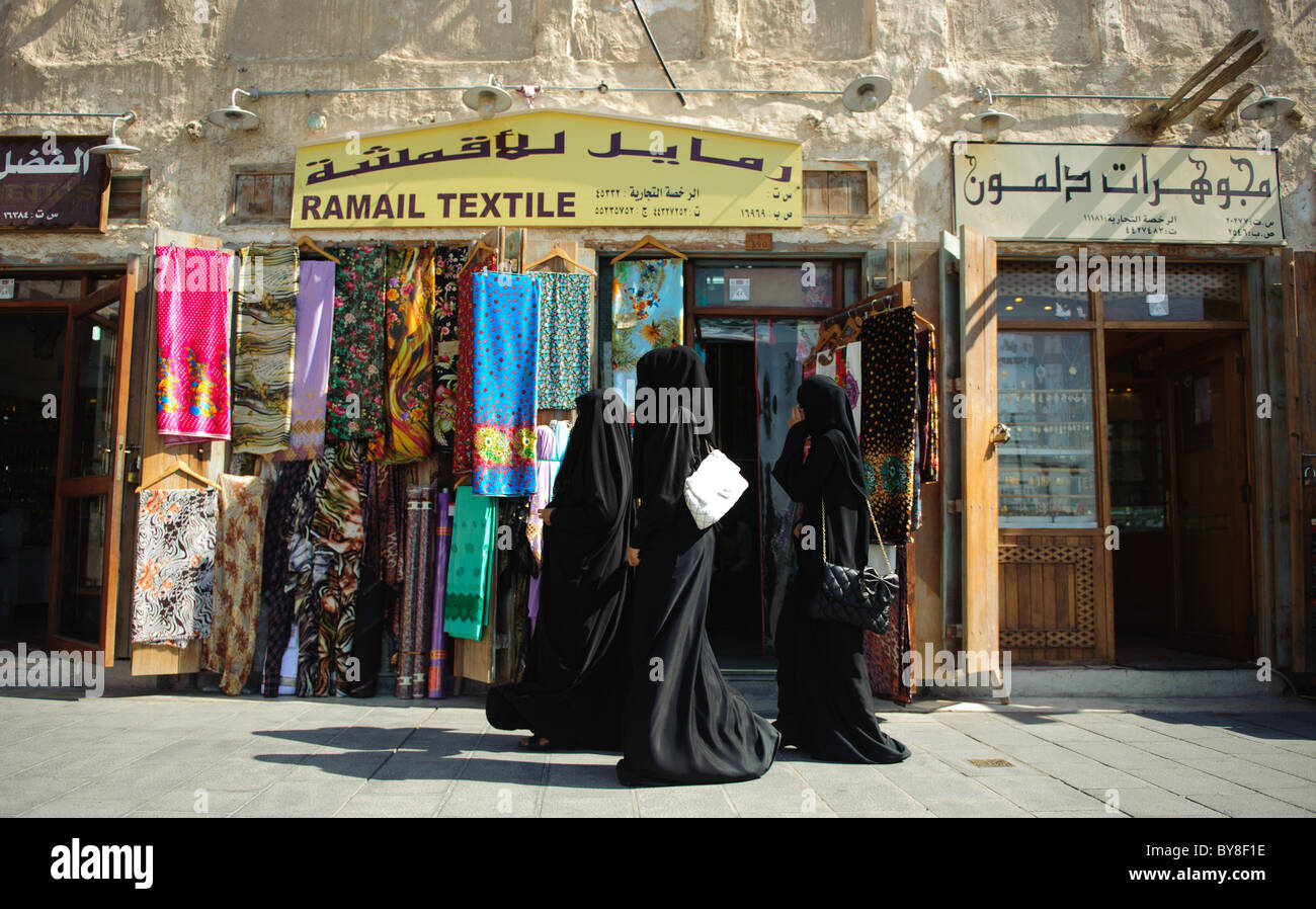 Trois femmes en noir robe arabe devant une boutique de textile dans la région de Souq Waqif à Doha, dans l'État du Qatar Banque D'Images