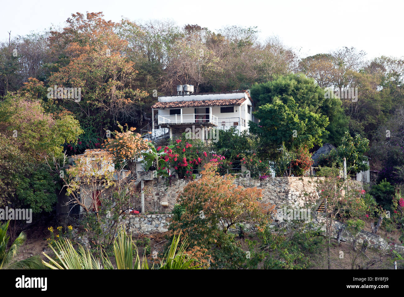 Jolie maison à flanc de murs de plâtre blanc toit tuile rouge des murs de soutènement en pierre une végétation tropicale Puerto Angel Banque D'Images