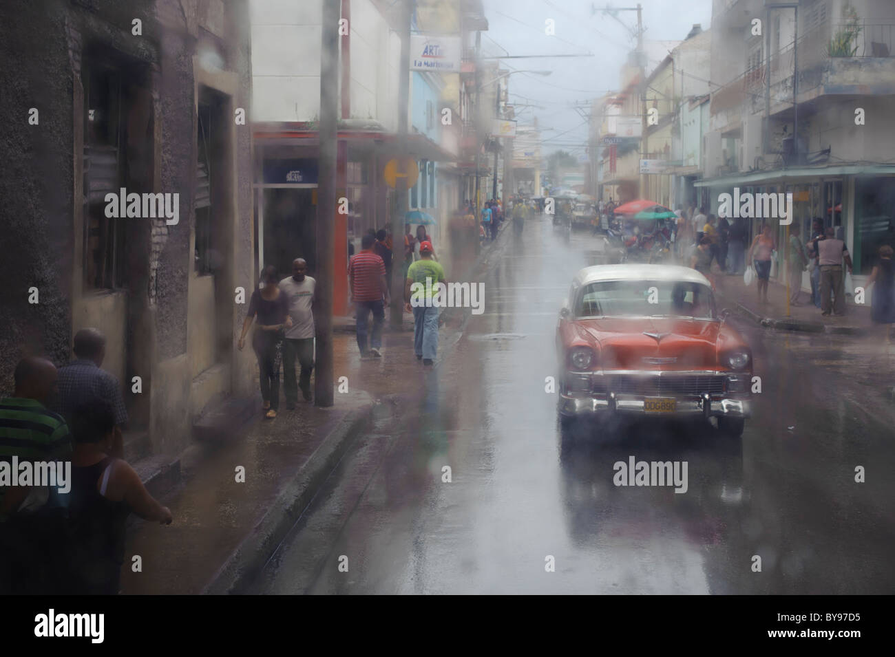 Vieille voiture rouge américaine classique dans une rue de Holguin Cuba pendant un jour pluvieux avec stop écrit sur la route Banque D'Images