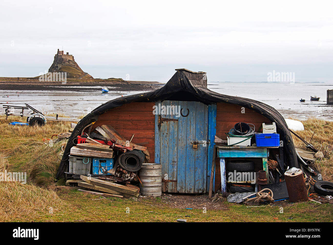 Bateaux de pêche en bois transformé en abris.Lindisfarne. Avec Château. L'île Sainte,Angleterre Northumberland Banque D'Images