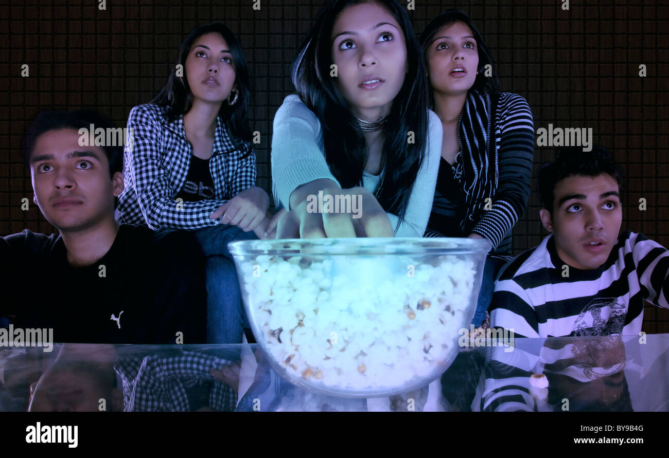 Girl popcorn tout en regardant un film avec ses amis Banque D'Images