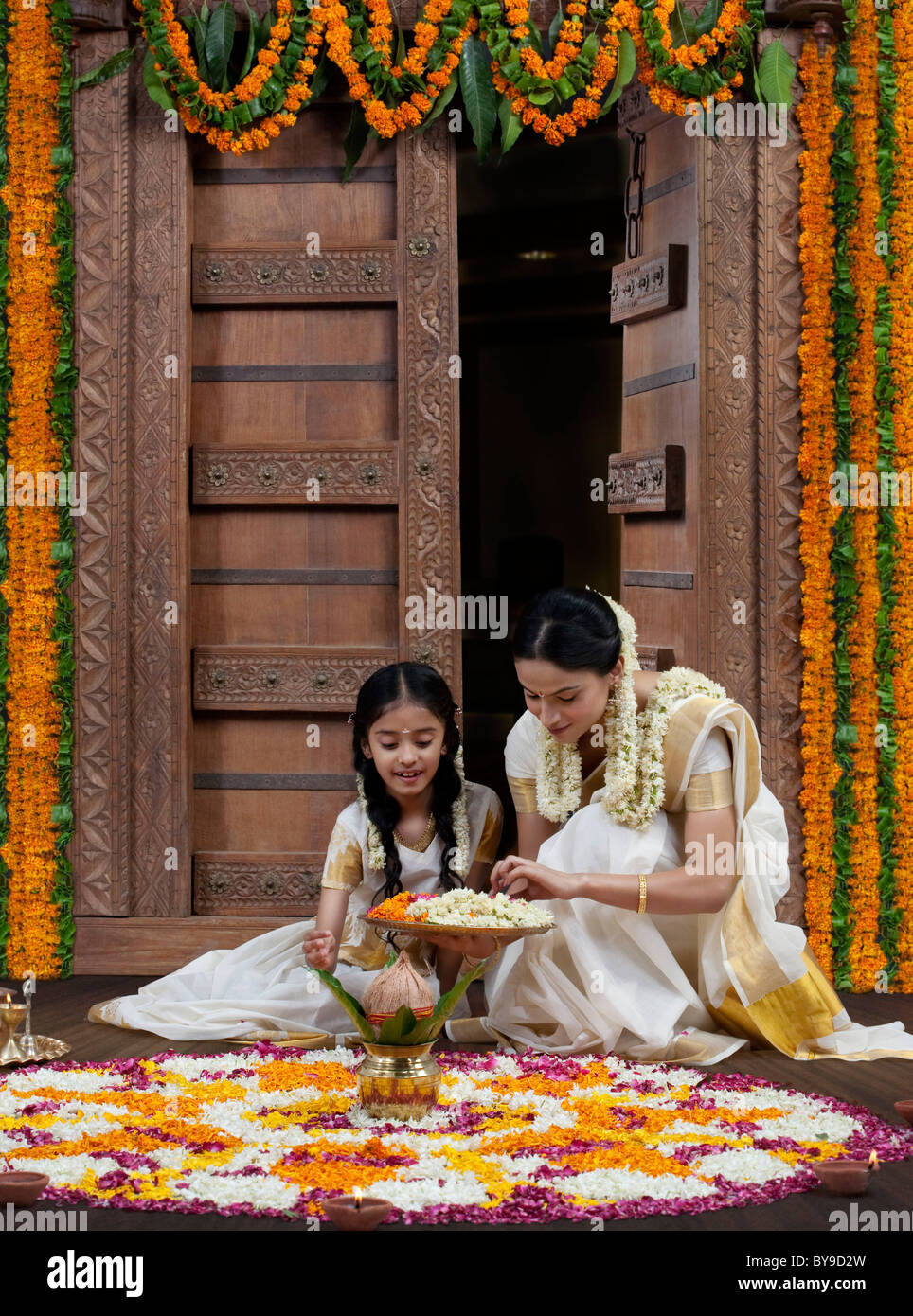 Femme du sud de l'Inde d'aider sa fille avec un rangoli Banque D'Images