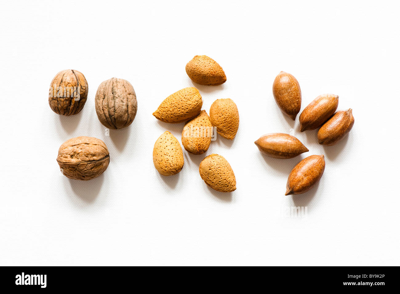 Trois noix, amandes et six cinq noix de pécan sur un fond blanc. Banque D'Images