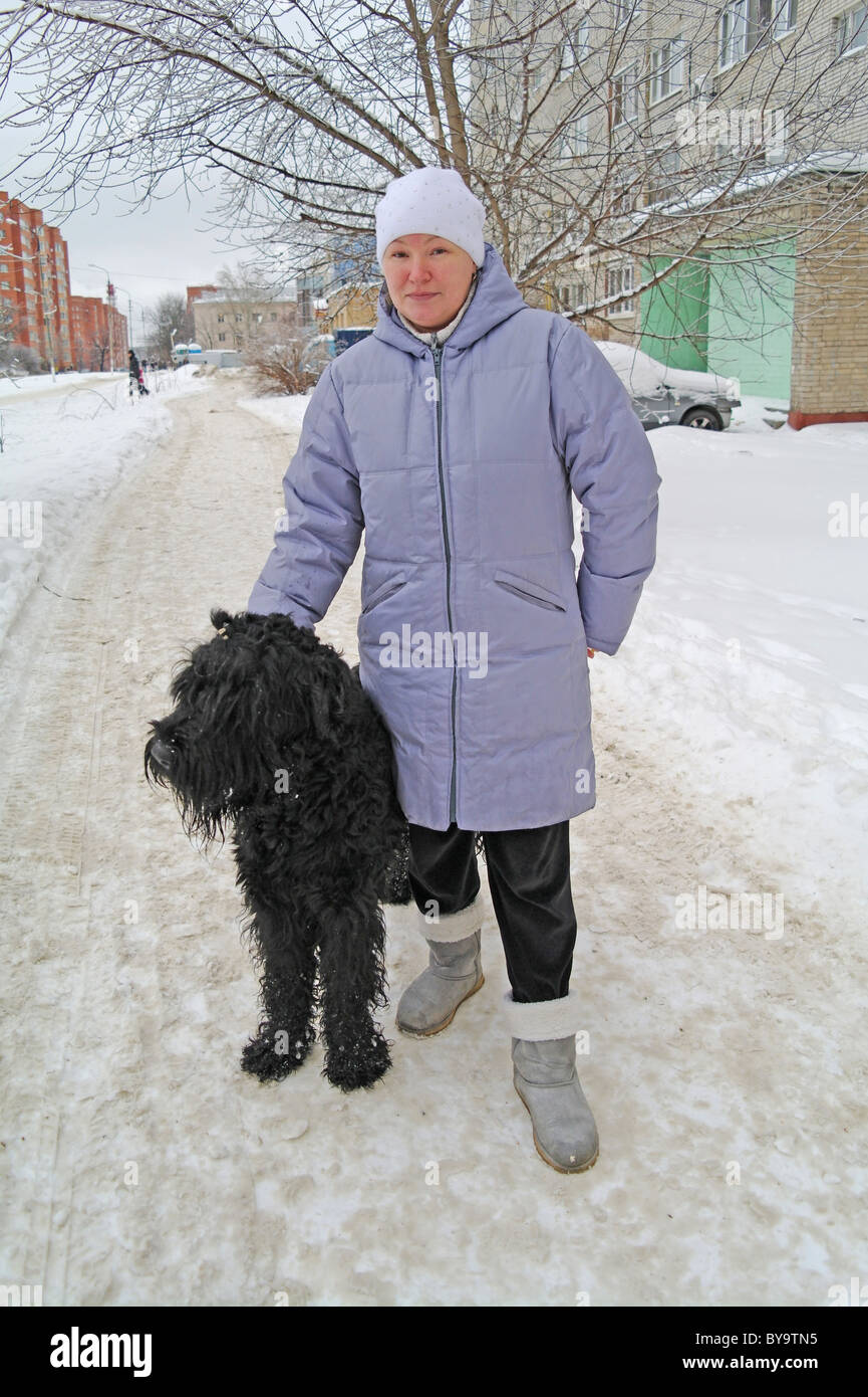 Chien Terrier Noir Russe avec la maîtresse dans la rue, l'hiver dans la région de Moscou, Russie Banque D'Images