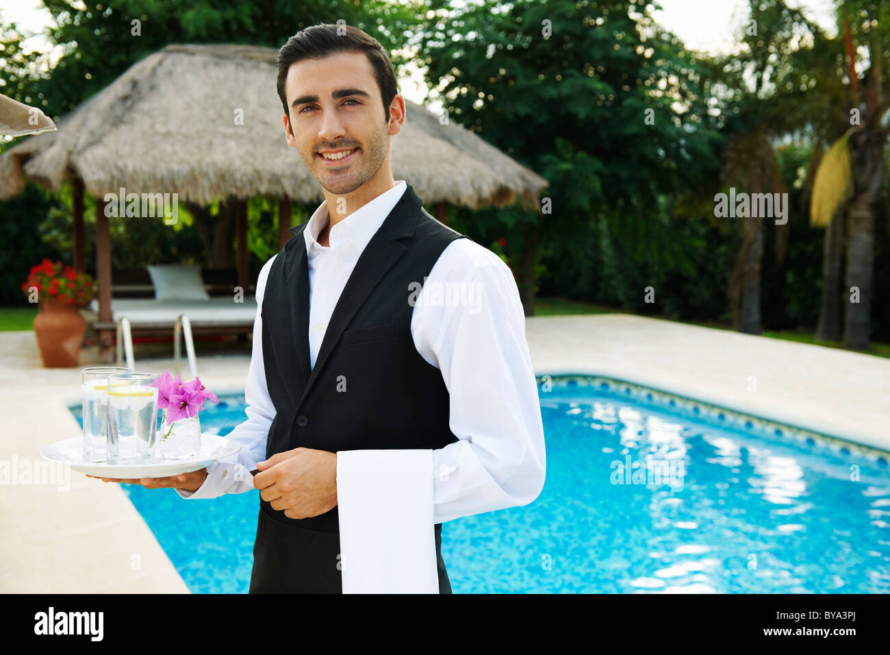 Hôtel waiter holding tray par piscine de l'hôtel Banque D'Images