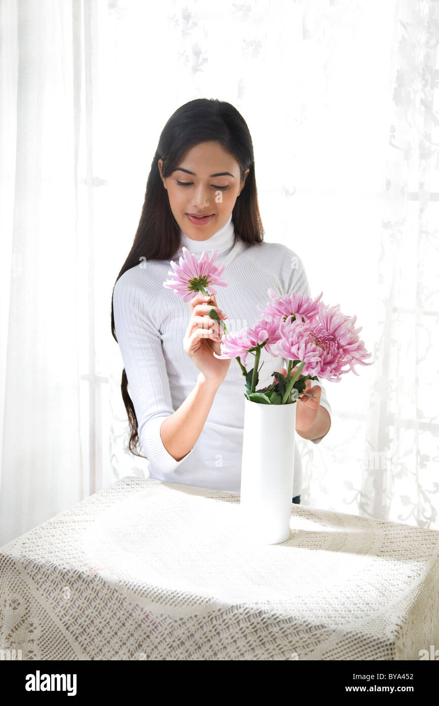 Young woman arranging flowers in vase Banque D'Images