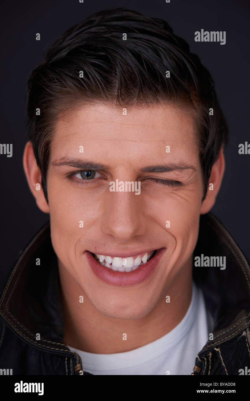 Jeune homme avec des dents blanches brillantes, avec un clin d', portrait Banque D'Images