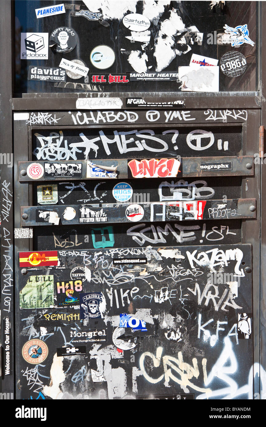 La porte en acier dans le bâtiment en briques au centre-ville de Portland, Maine est recouverte d'autocollants et de graffitis Banque D'Images