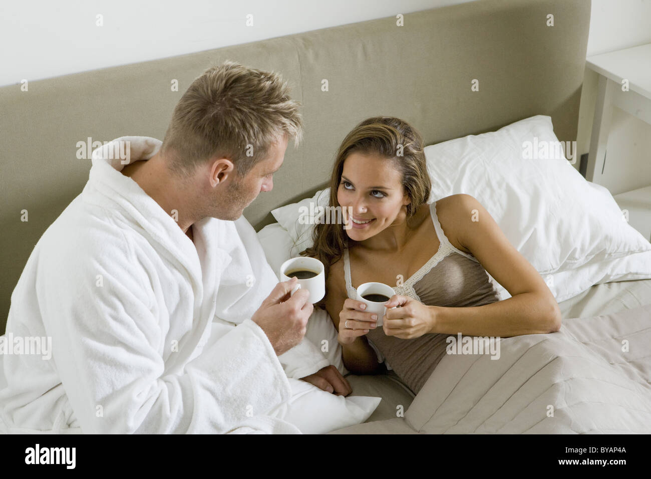 Jeune couple drinking coffee in bed Banque D'Images