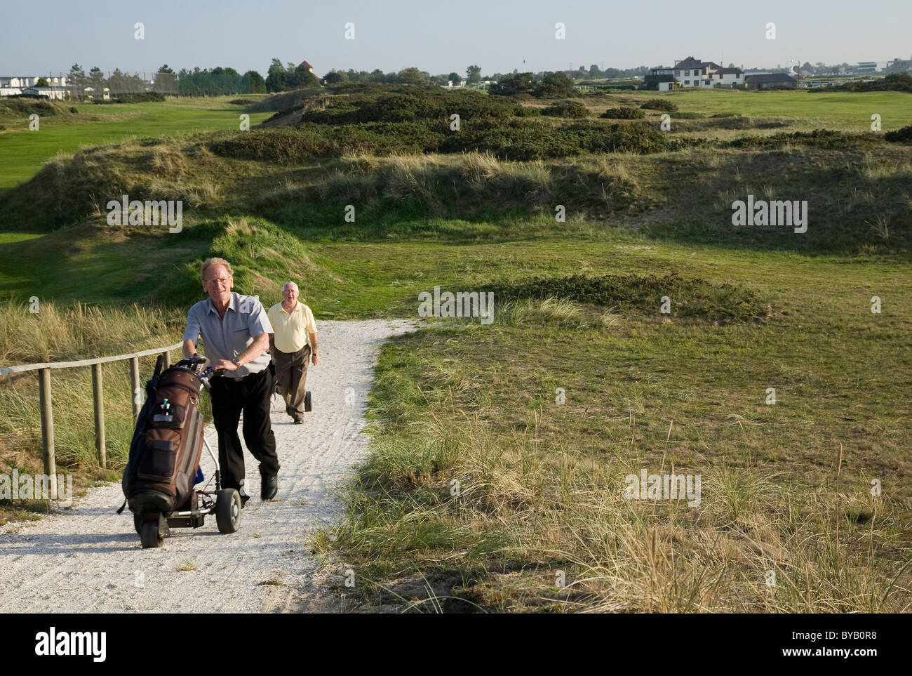 Deux golfeurs à marcher avec leurs caddies sur Caister golf course Banque D'Images