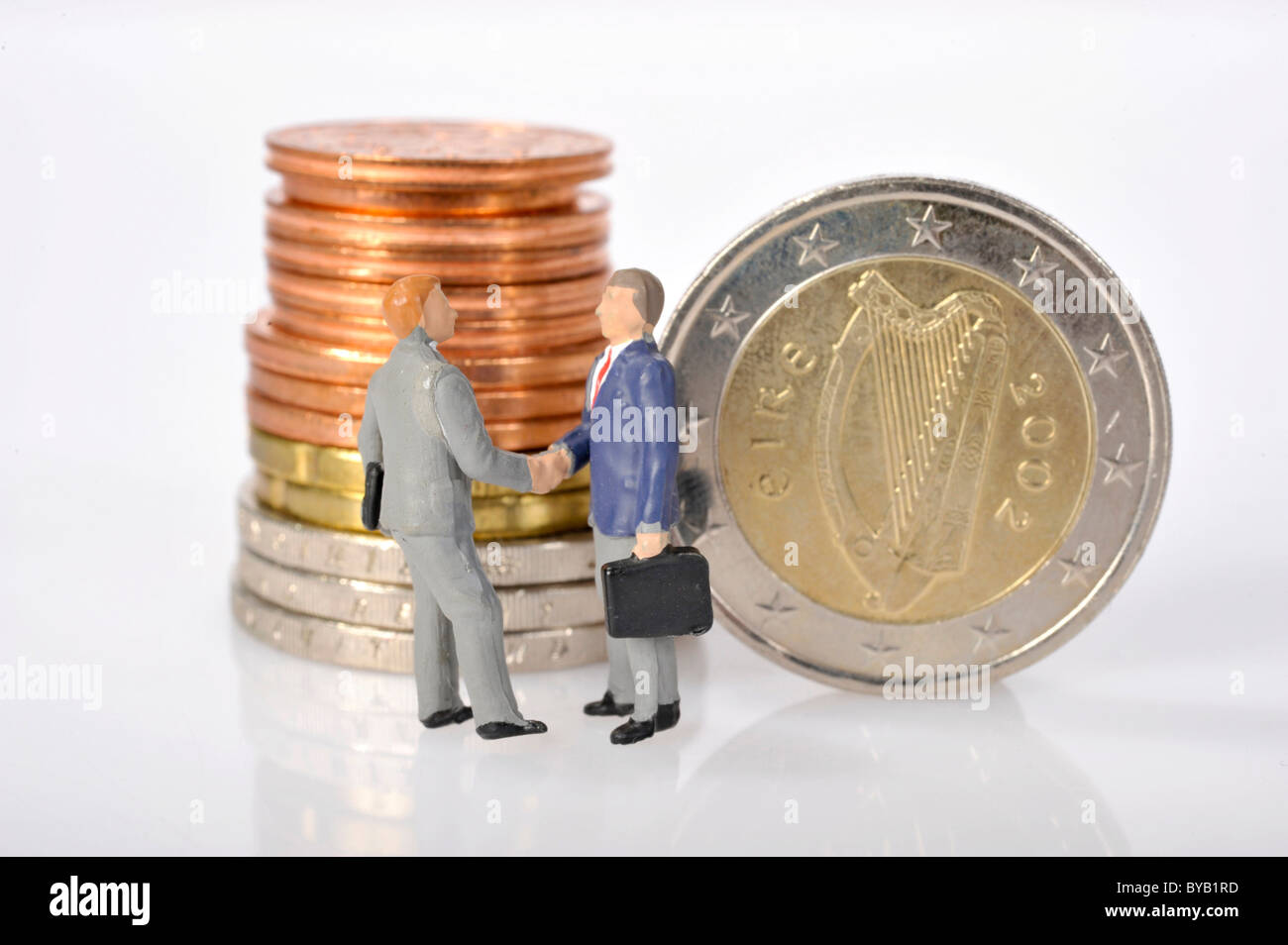 Univers miniatures se serrer la main, des pièces en euros irlandais, image symbolique de la crise financière en Irlande Banque D'Images