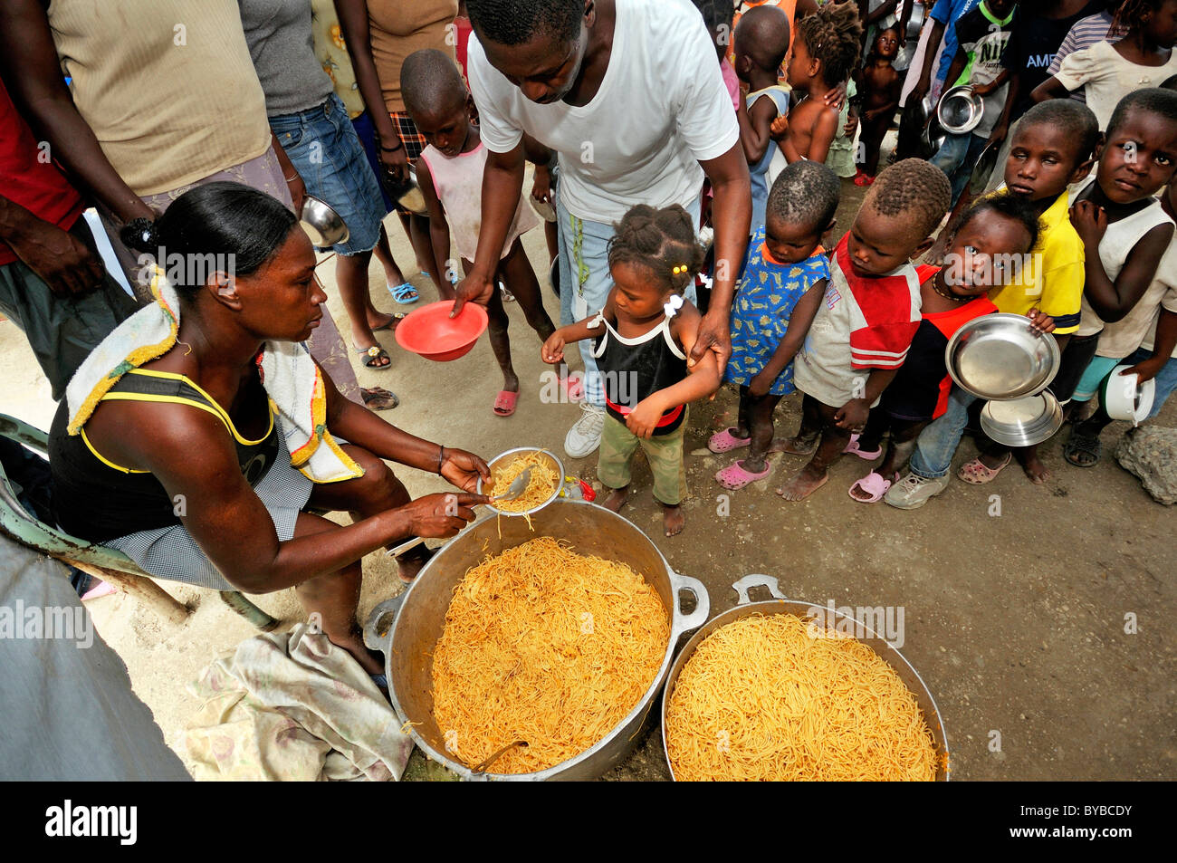 La distribution de denrées alimentaires aux enfants nécessiteux dans un camp pour les victimes du tremblement de terre de janvier 2010, Croix-des-Bouquets, district , Haïti Banque D'Images