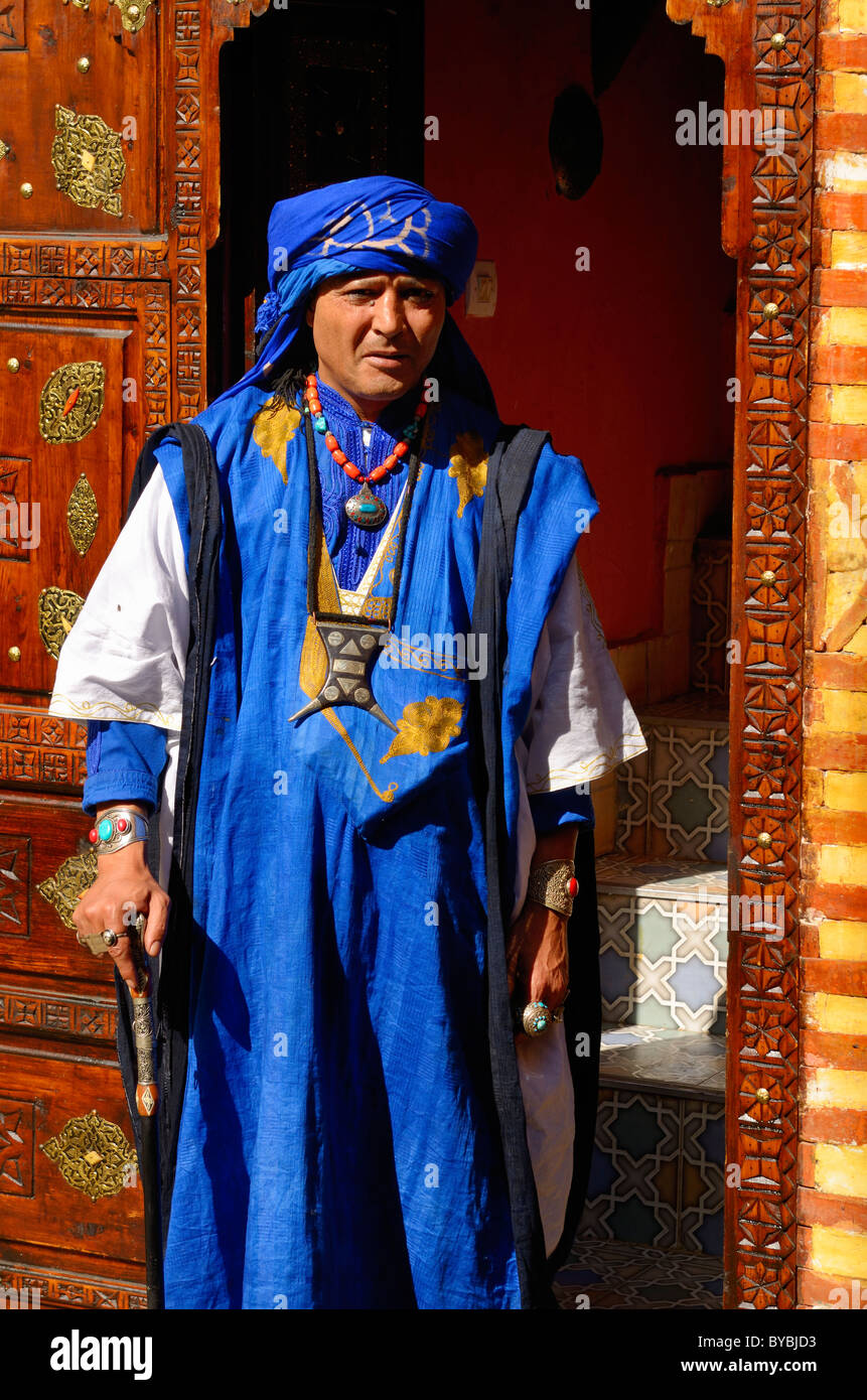 L'homme en costume traditionnel berbère bleu debout dans incrustations aux bois sculpté porte marrakech maroc Banque D'Images